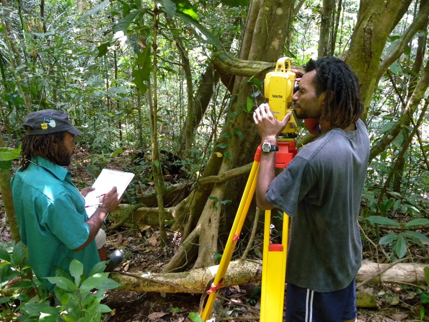 Two men collecting data in the forest using machinery.