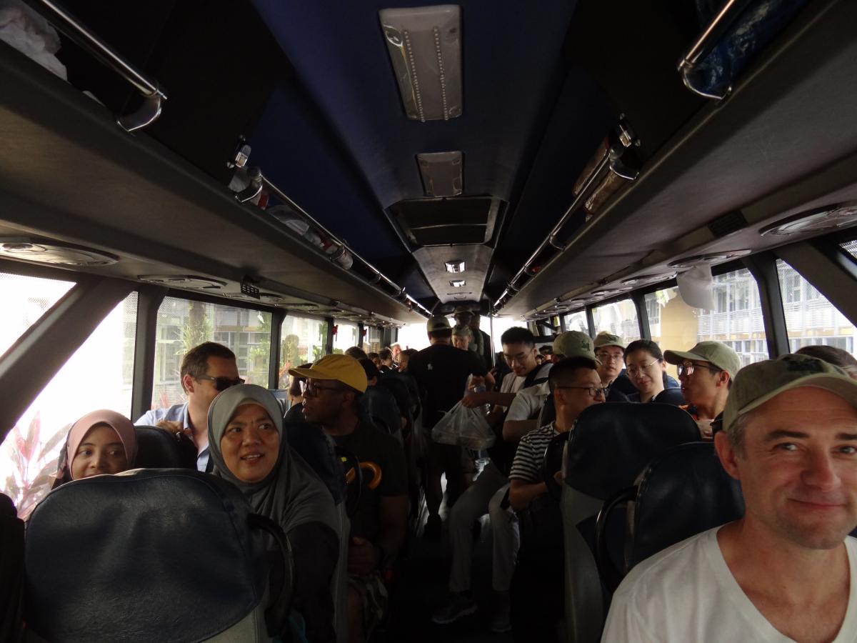 Two rows of seated passengers inside a bus.