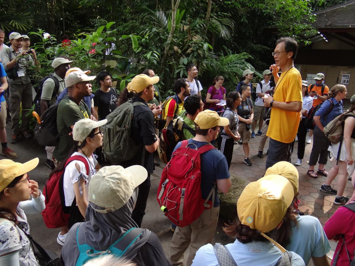 Workshop participants listen intently as Shawn Lum lectures outside.