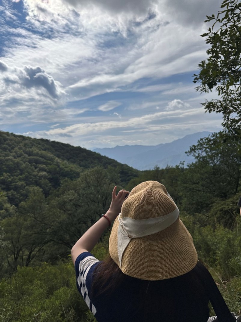 A woman wearing a hat takes a photo of the beautiful mountain view