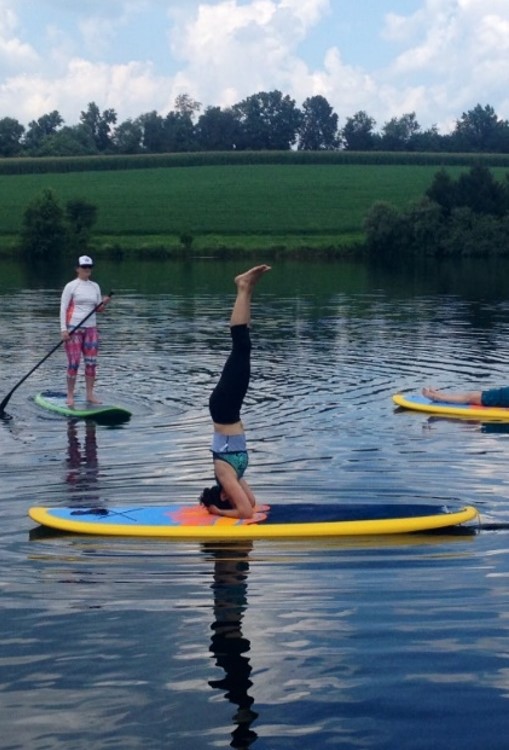 Erika doing a headstand on a paddleboard.